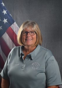 Portrait of Commissioner Hathaway in Class A uniform in front of American flag backdrop