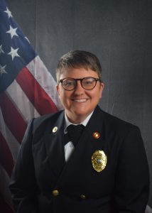 Portrait of Alexis McLellan in a Class A uniform in front of an American flag backdrop