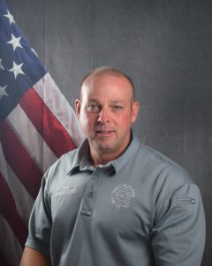 Portrait of Commissioner Stirns in front of American flag backdrop