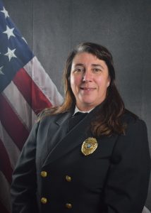 Portrait of Kassandra Whidden in Class A uniform in front of draped American Flag