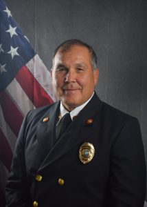 Portrait of Don Wilkinson in Class A uniform in front of American flag backdrop