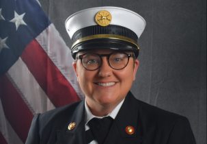 Portrait of Alexis McLellan in a Class A uniform in front of an American flag backdrop